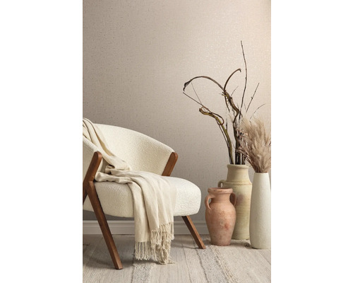 Decoratief interieur met fauteuil, deken, vazen en siergrassen voor een wand met textielbehang.