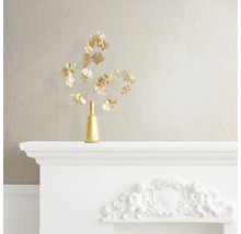 Decoratief stilleven met gouden vaas en ginkgo takken op een witte schoorsteenmantel.