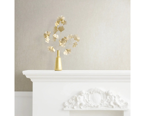 Decoratief stilleven met gouden vaas en ginkgo takken op een witte schoorsteenmantel.