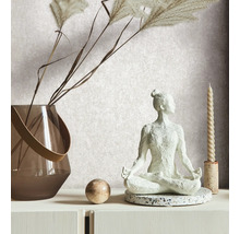 Decoratieve scène met een yogafiguur, een vaas met siergras, een bol en een kaars op een witte ladekast.