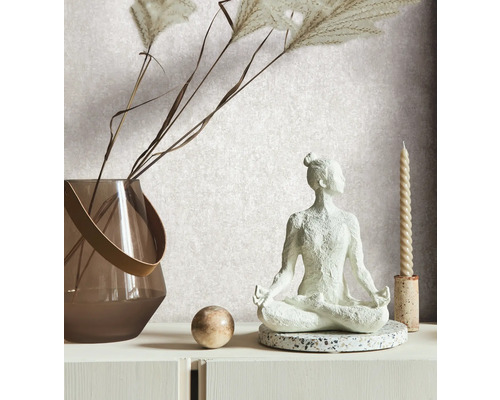 Decoratieve scène met een yogafiguur, een vaas met siergras, een bol en een kaars op een witte ladekast.
