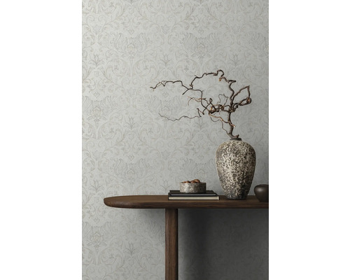 Gedetailleerd beeld van een versierde wand met bloemenbehang, een houten tafel met decoraties en een vaas met takken.