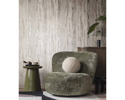 Woonkamer met patroonbehang, fauteuil en bijzettafel.