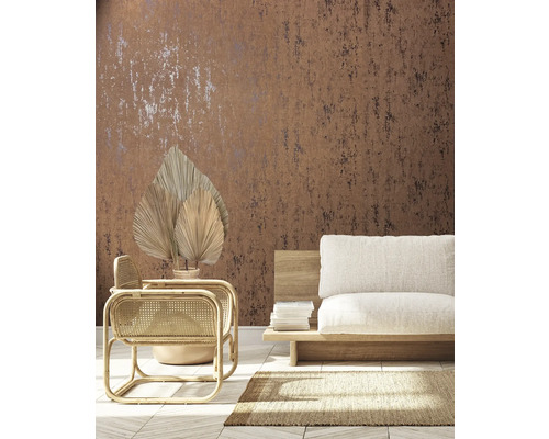 Woonkamer met bruin patroonbehang, rotan stoel en beige bank