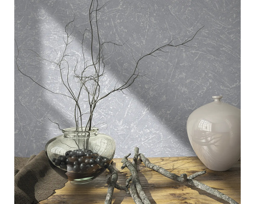 Decoratieve opstelling met vaas, takken en decoratieve stenen op een houten tafel voor een gestructureerde muur.