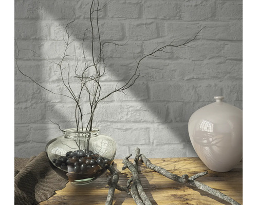 Decoratieve opstelling met een glazen vaas, takken en een keramische vaas op een houten tafel