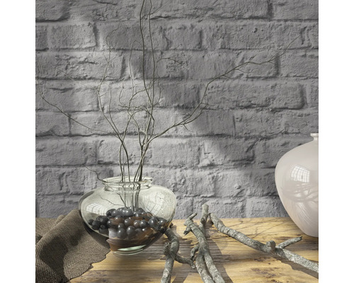 Decoratieve takken in glazen vaas op houten tafel voor bakstenen muur