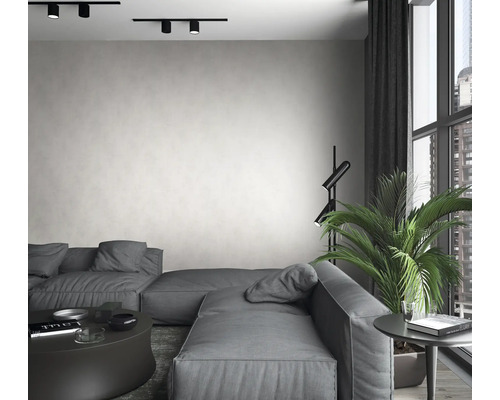 Woonkamer met grijze bank, vloerlamp, kamerplant en plafondlampen.