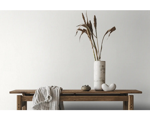 Decoratieve opstelling met bank, vaas, siergras en textiel binnenshuis.