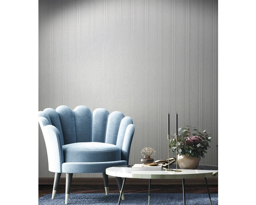 Inrichtingsvoorbeeld met fauteuil, tafel en wandbehang in een lichte kamer.