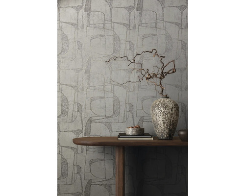 Een muur met grafisch behang, gedecoreerd met een houten vaas op een tafel.