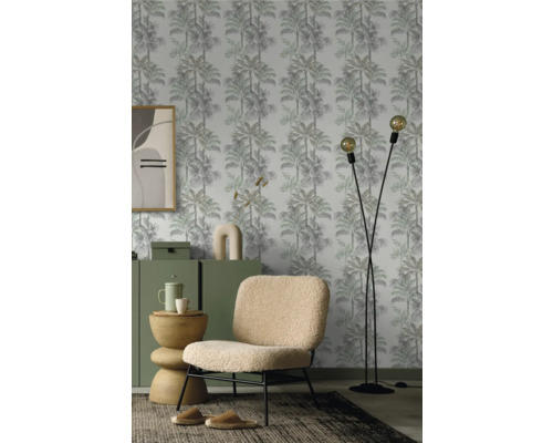 Woonkamer met palmenprint behang, fauteuil en vloerlamp.