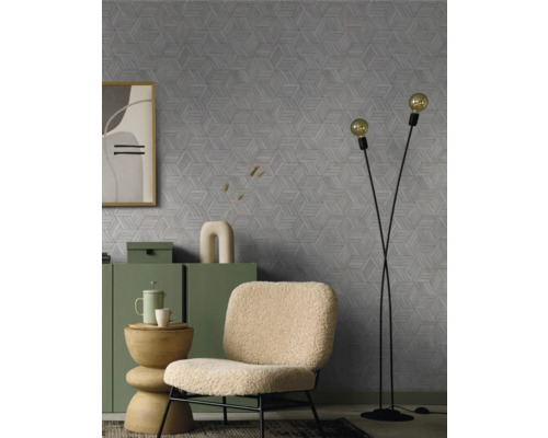 Woonkamer met een fauteuil, staande lamp en een dressoir voor een muur met een geometrisch patroon.