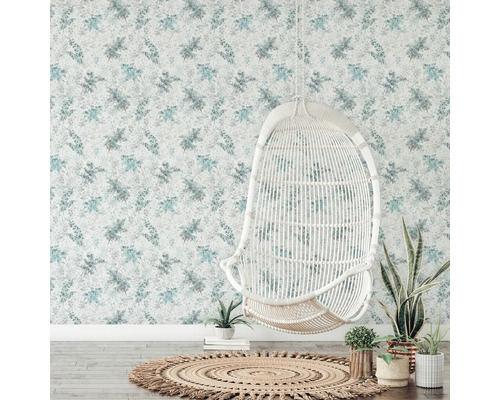 Decoratieve kamer met bloemenbehang, rotan stoel en rond vloerkleed.
