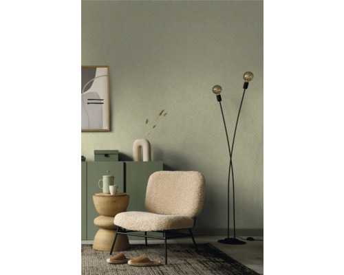 Woonkamer met groen behang met patroon, fauteuil, staande lamp en tapijt