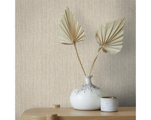 Close-up van een muur met gebreid patroonbehang, gedecoreerd met een vaas en gedroogde palmbladeren op een houten tafel.