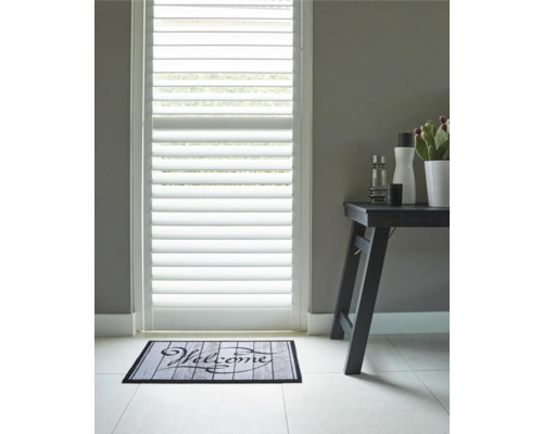 Scene met deurjaloezieën, deurmat met opschrift Welkom en bijzettafel met decoratieartikelen