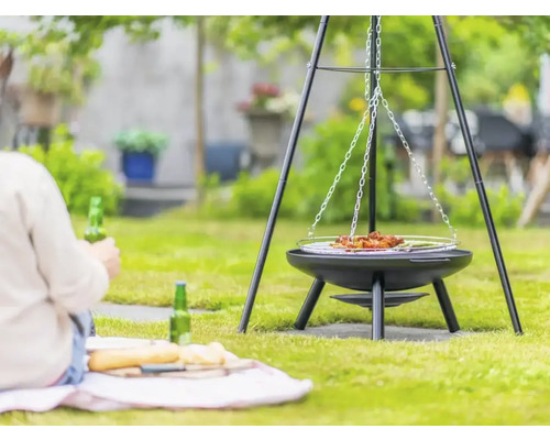 Driepoot barbecue in de tuin met persoon op de achtergrond