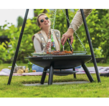 Persoon grilt vlees op een driepootgrill in de tuin