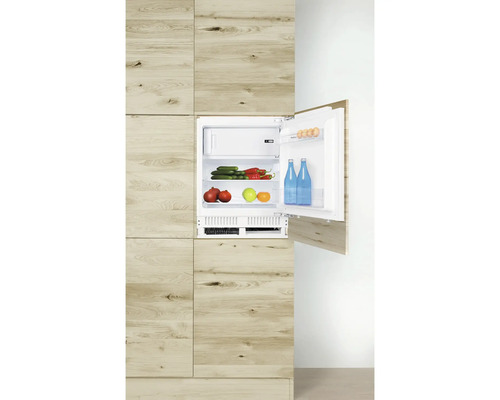 Ingebouwde koelkast in houtlook met geopende deur, gevuld met levensmiddelen.