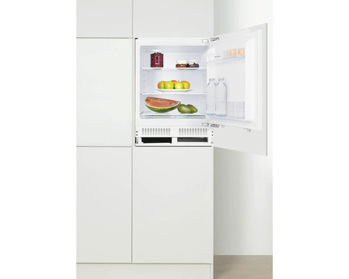 Ingebouwde koelkast met open deur, gevuld met levensmiddelen in witte keuken