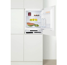 Geopende inbouwkoelkast gevuld met voedsel in een witte keuken.