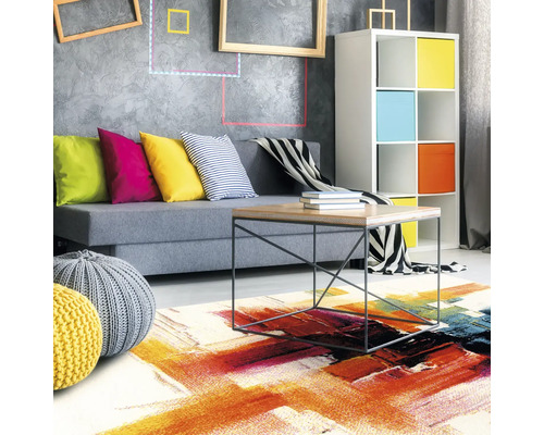 Woonkamer met bank, kussens, vloerkleed en rekken voor een levendige sfeer