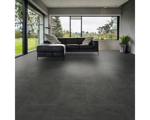 Moderne woonkamer met grootformaat grijze vloertegels en een zwarte leren bank