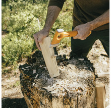 Een persoon hakt hout met een kloofbijl op een hakblok.