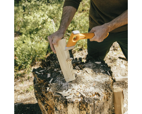 Een persoon hakt hout met een kloofbijl op een hakblok.