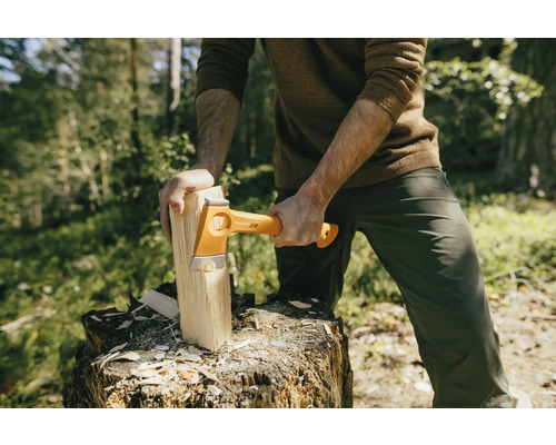 Man hakt hout met een Fiskars kloofbijl op een boomstronk