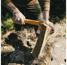 Iemand hakt hout met een kloofbijl op een hakblok.