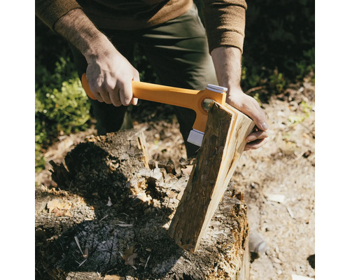 Iemand hakt hout met een kloofbijl op een hakblok.