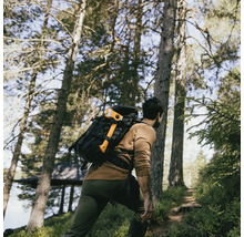 Man met rugzak en bijl wandelt door het bos