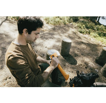 Man zit in het bos en houdt een bijl vast.