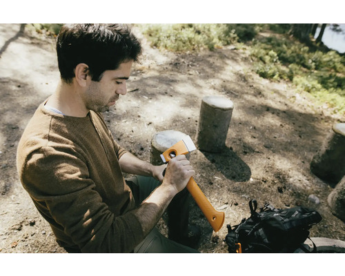 Man zit in het bos en houdt een bijl vast.
