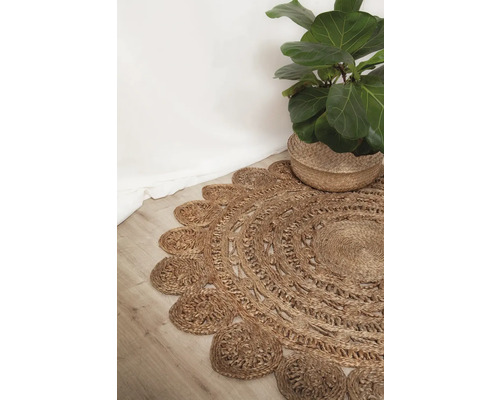 Rond vloerkleed van natuurlijke vezels met decoratieve rand en kamerplant in mand