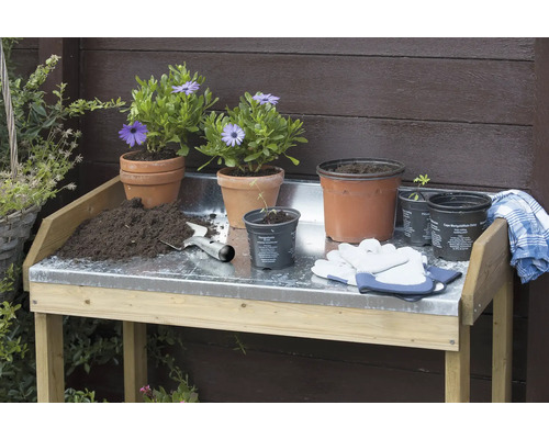 Tuiniertafel met bloempotten, potgrond, handschoenen en een tuinschep