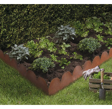 Bloembed met planten, metalen bloembedrand, tuingereedschap en handschoenen
