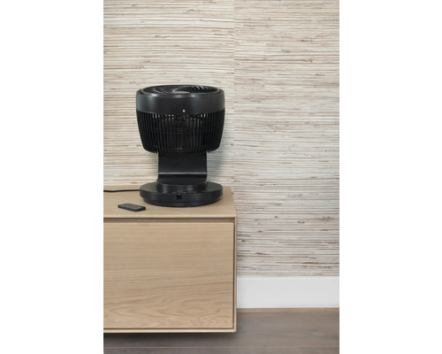 Zwarte ventilator met afstandsbediening op een houten kast