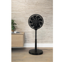 Zwarte ventilator op een houten vloer voor een wand met patroon