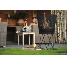 Metalen vuurkorf met brandend hout in een tuinomgeving.