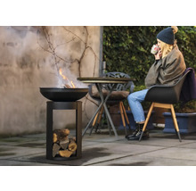 Vuurschaal met hout en vrouw in de tuin
