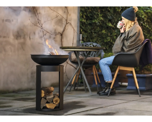 Vuurschaal met hout en vrouw in de tuin