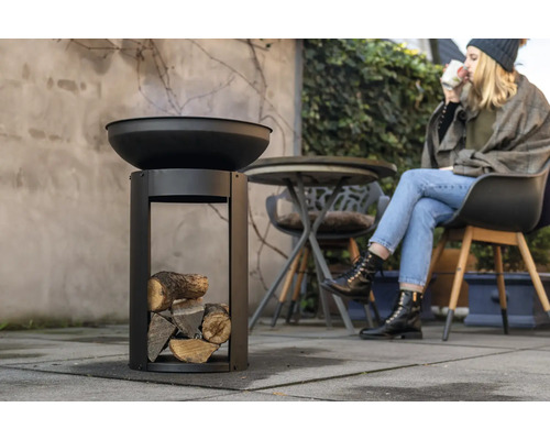 Vuurschaal met hout en zittende persoon buiten