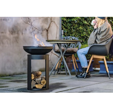 Vuurplaats met hout en persoon op de achtergrond
