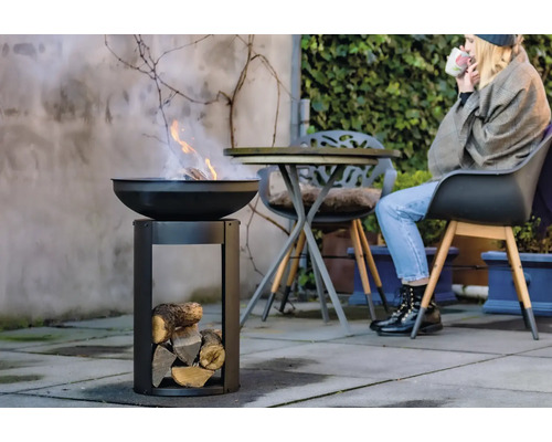 Vuurplaats met hout en persoon op de achtergrond