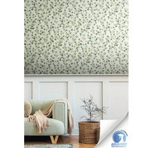 Woonkamer met een muur met behang met bladmotief, een bank en een plant in een mand