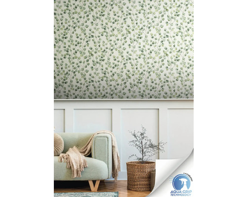 Woonkamer met een muur met behang met bladmotief, een bank en een plant in een mand