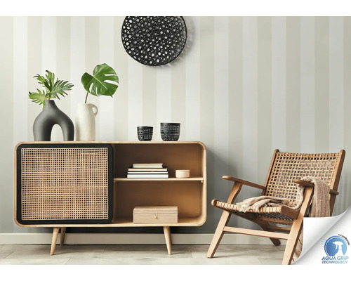 Woonkamerscène met dressoir, decoratie en rotan stoel voor een gestreepte muur